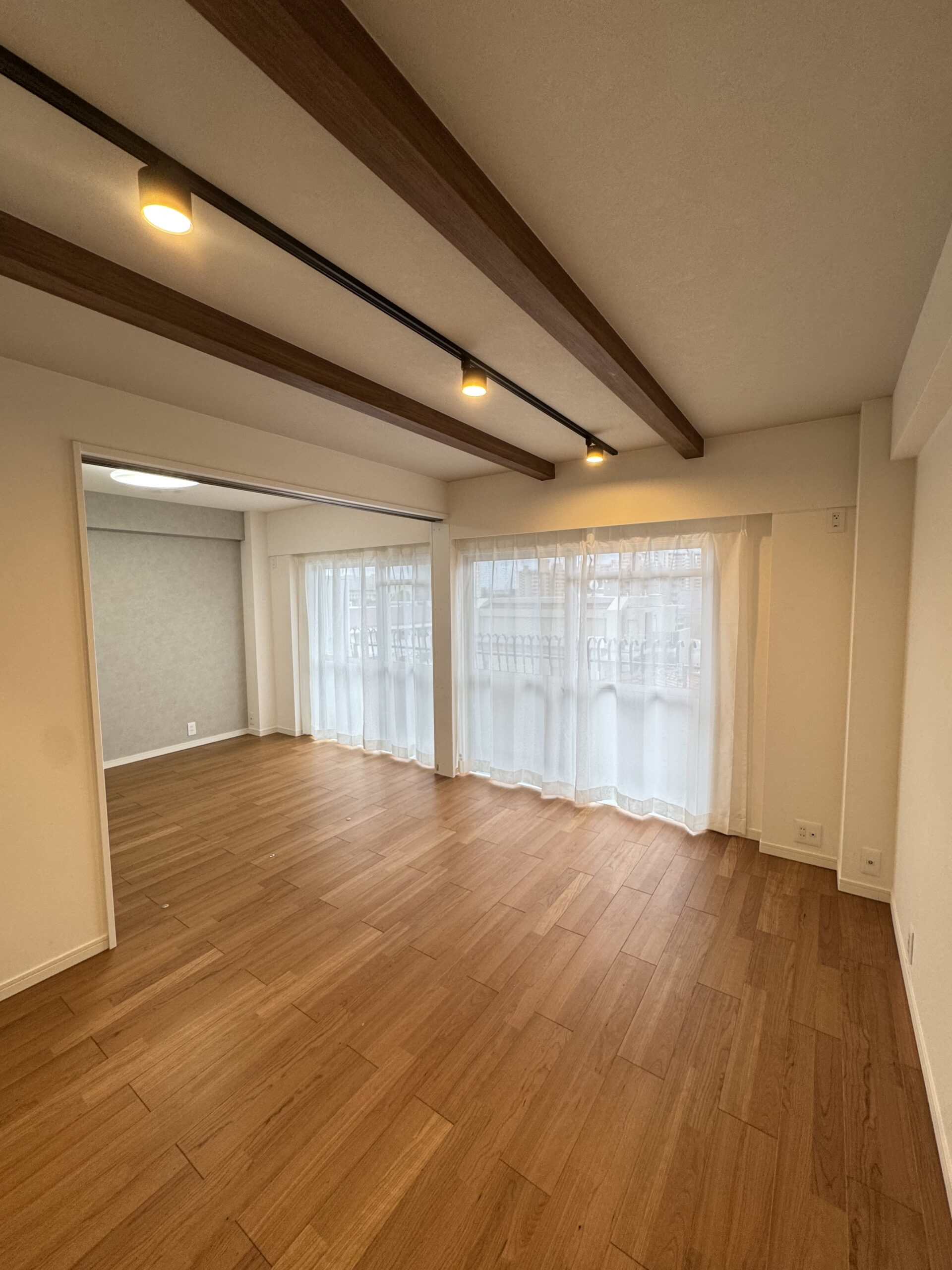 天井の化粧梁と、格子入りのドアが印象的なリビング。可愛らしさのなかに、キッチンのグレータイルで上品さもプラスした内装に。