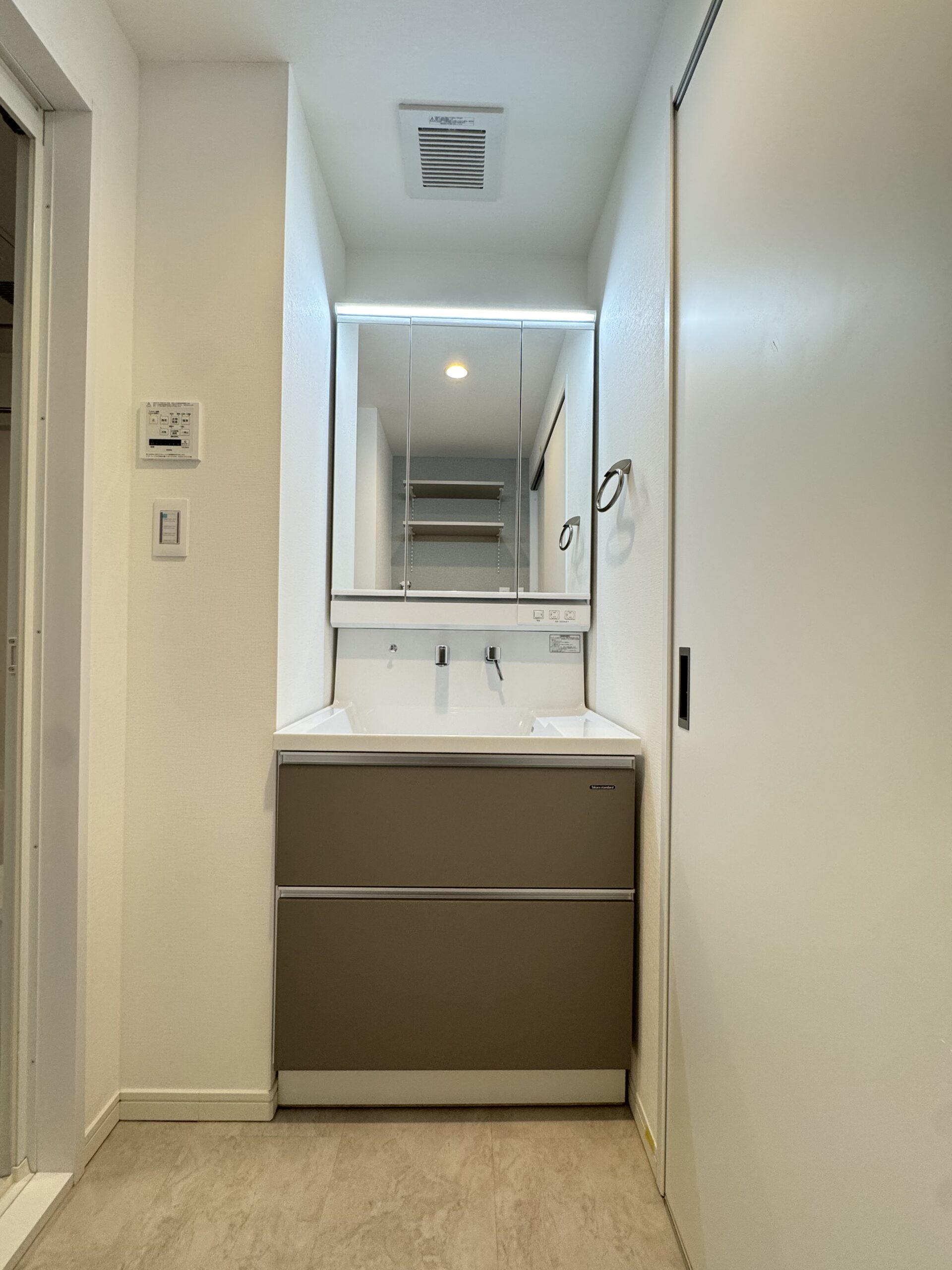 突板の天井材とフローリングが温もりを感じるリビング。アクセントで施工したエコカラットとタイルが木と調和し、心地の良い空間に。